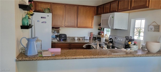 kitchen with white appliances and dark stone countertops