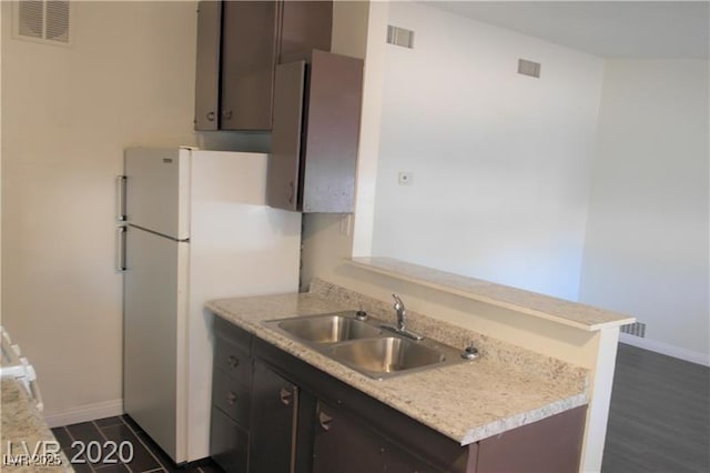 kitchen with dark hardwood / wood-style floors, sink, white fridge, and dark brown cabinetry