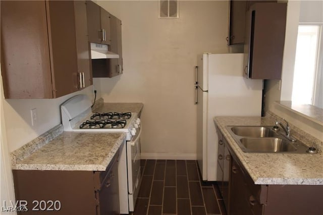 kitchen featuring sink, dark brown cabinets, and white appliances