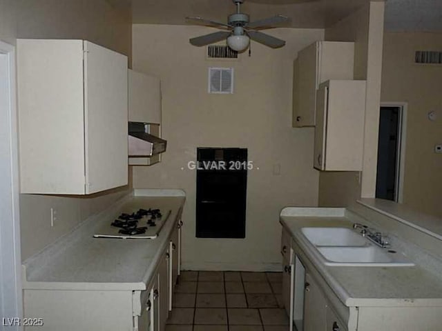 kitchen with white cabinetry, ceiling fan, dark tile patterned flooring, white gas stovetop, and sink