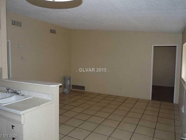 washroom with sink, a textured ceiling, and light tile patterned floors