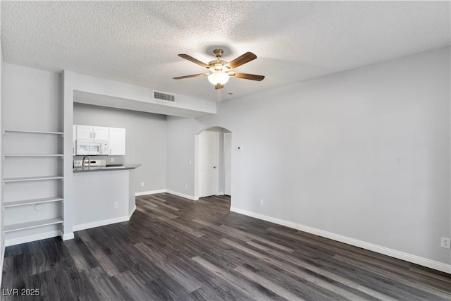 unfurnished living room featuring ceiling fan, a textured ceiling, and dark hardwood / wood-style floors