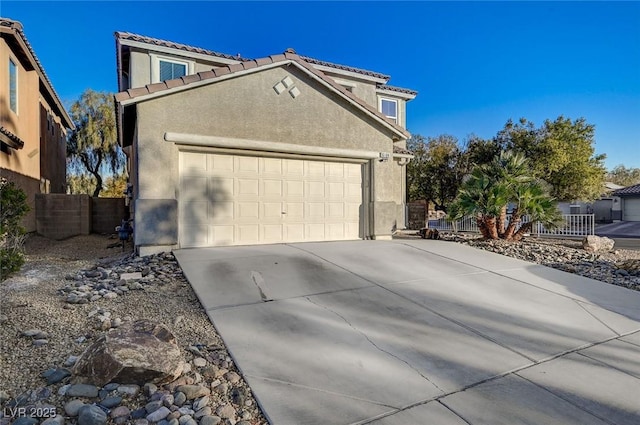 view of side of home featuring driveway, an attached garage, fence, and stucco siding