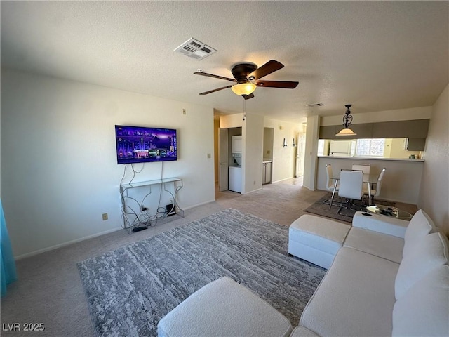 living room with light carpet, ceiling fan, and a textured ceiling