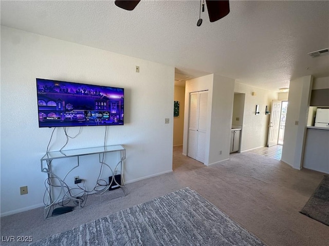 unfurnished living room with ceiling fan, light colored carpet, and a textured ceiling