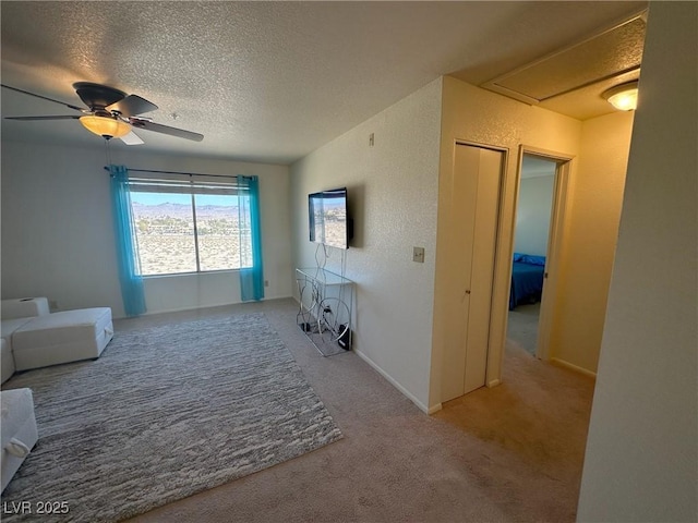 carpeted living room featuring ceiling fan and a textured ceiling