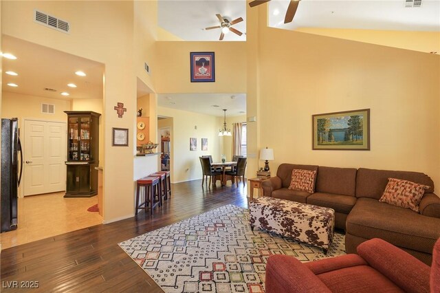 living room featuring dark wood-type flooring and ceiling fan with notable chandelier