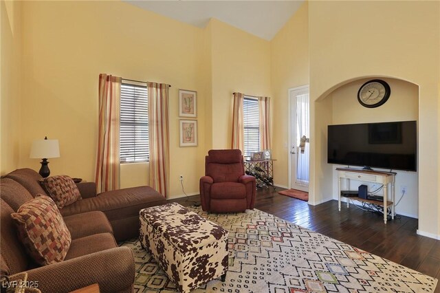 living room with a high ceiling, a wealth of natural light, and dark hardwood / wood-style flooring