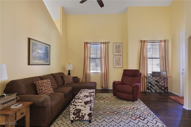 living room featuring dark wood-type flooring, a healthy amount of sunlight, and ceiling fan