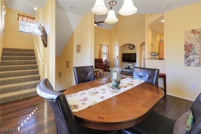 dining area with high vaulted ceiling, ceiling fan with notable chandelier, dark hardwood / wood-style flooring, and a healthy amount of sunlight