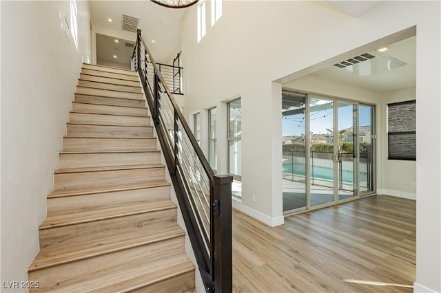 stairs featuring wood-type flooring and a towering ceiling