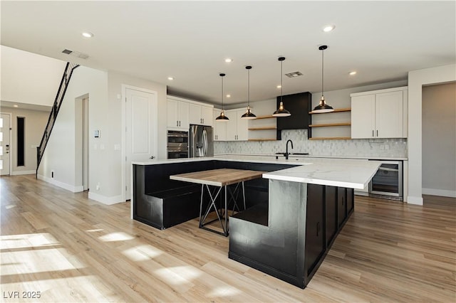 kitchen featuring sink, stainless steel fridge, white cabinetry, a spacious island, and beverage cooler