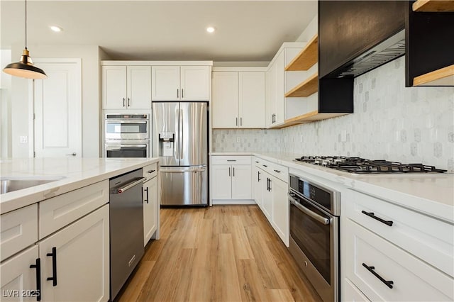 kitchen featuring white cabinetry, appliances with stainless steel finishes, light stone countertops, and hanging light fixtures