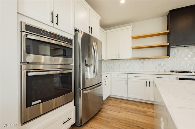 kitchen featuring light stone countertops, white cabinetry, appliances with stainless steel finishes, and light hardwood / wood-style floors