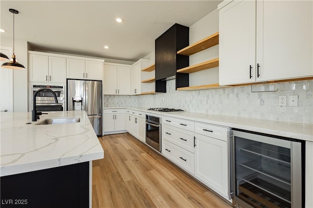 kitchen featuring white cabinetry, hanging light fixtures, stainless steel appliances, light stone countertops, and beverage cooler