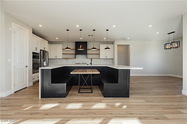 kitchen with stainless steel refrigerator, backsplash, a center island, white cabinets, and decorative light fixtures