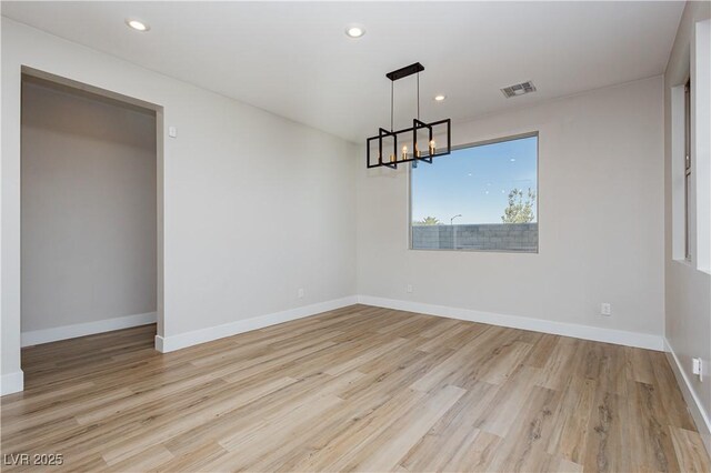 unfurnished dining area featuring a notable chandelier and light hardwood / wood-style flooring