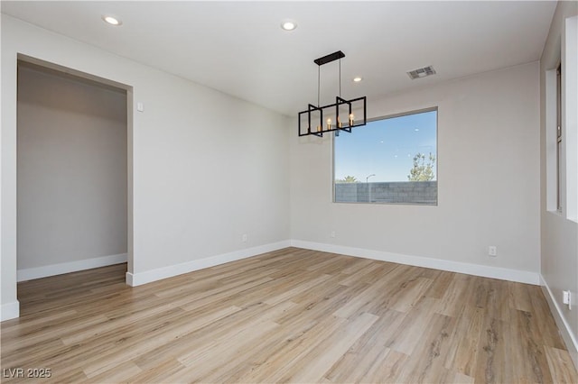 empty room with an inviting chandelier and light wood-type flooring