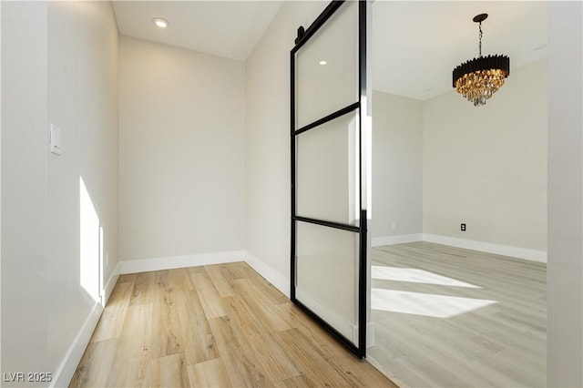 unfurnished room featuring a chandelier and light hardwood / wood-style floors