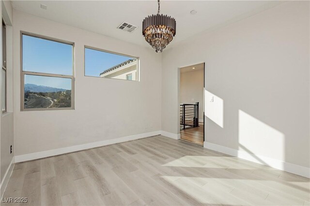 unfurnished room featuring light wood-type flooring and an inviting chandelier