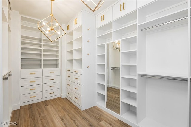 walk in closet with an inviting chandelier and light hardwood / wood-style floors