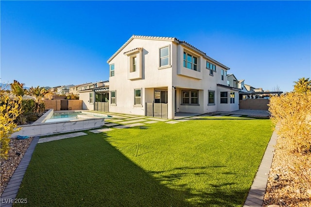 rear view of house with a swimming pool with hot tub, a yard, and a patio