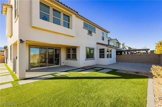 rear view of house featuring a yard and a patio area