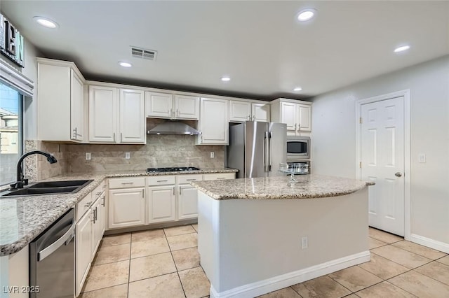 kitchen featuring a kitchen island, light tile patterned flooring, white cabinetry, stainless steel appliances, and light stone counters