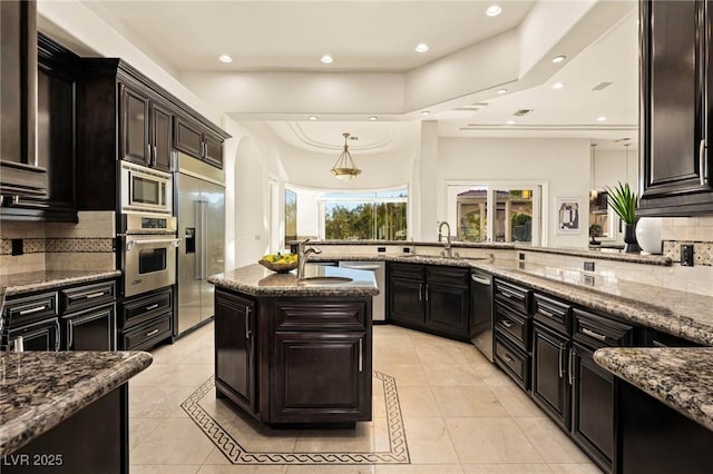 kitchen featuring tasteful backsplash, sink, built in appliances, and a kitchen island with sink