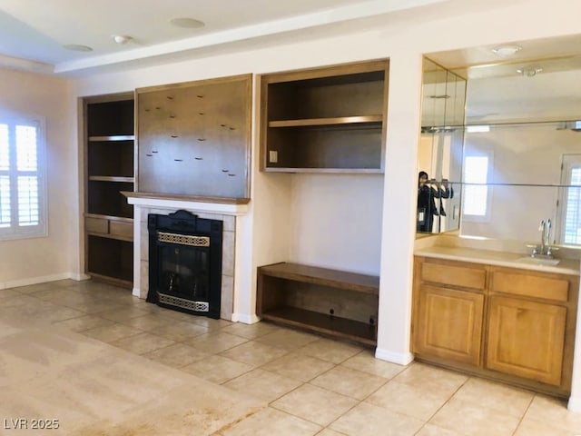 unfurnished living room featuring light tile patterned flooring, sink, and a fireplace