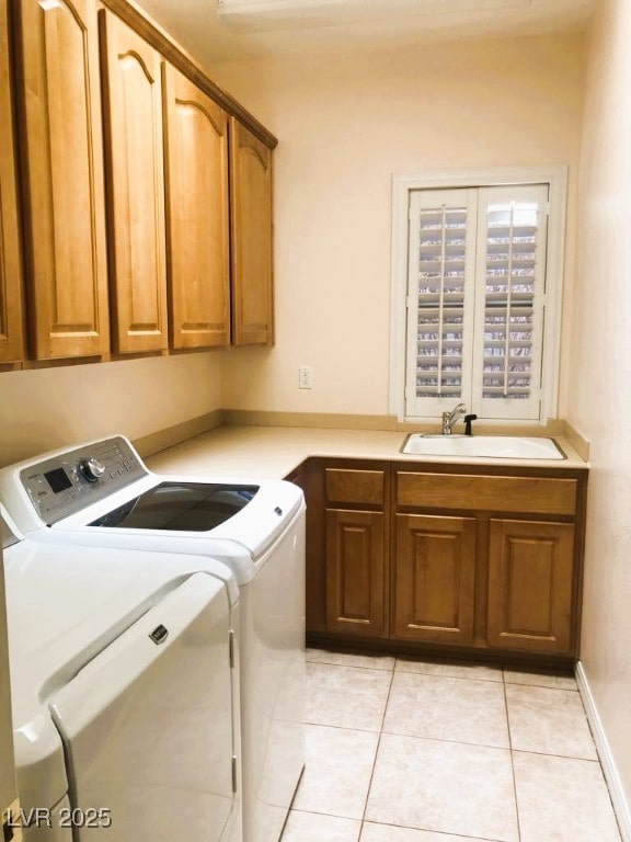 laundry area with light tile patterned flooring, cabinets, washer and dryer, and sink