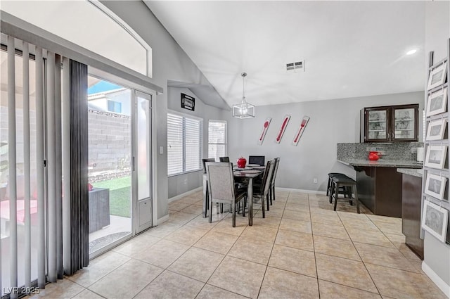 tiled dining room with a chandelier and lofted ceiling