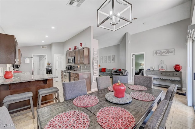 tiled dining area with sink, vaulted ceiling, and an inviting chandelier