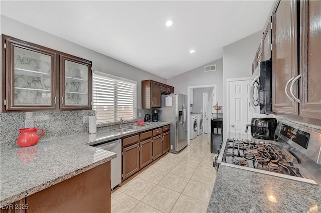 kitchen with tasteful backsplash, vaulted ceiling, washer and clothes dryer, and appliances with stainless steel finishes