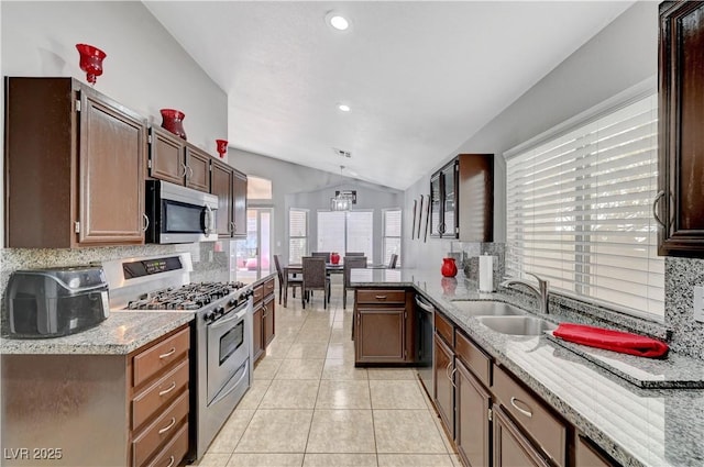 kitchen with pendant lighting, sink, backsplash, lofted ceiling, and stainless steel appliances