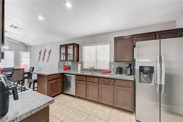 kitchen featuring vaulted ceiling, sink, kitchen peninsula, backsplash, and stainless steel appliances