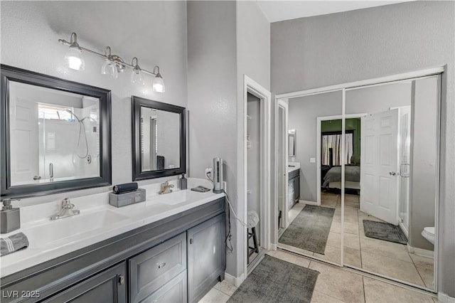 bathroom featuring toilet, vanity, walk in shower, and tile patterned flooring