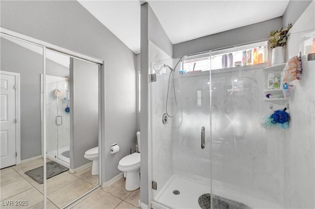 bathroom featuring toilet, tile patterned floors, vaulted ceiling, and a shower with door