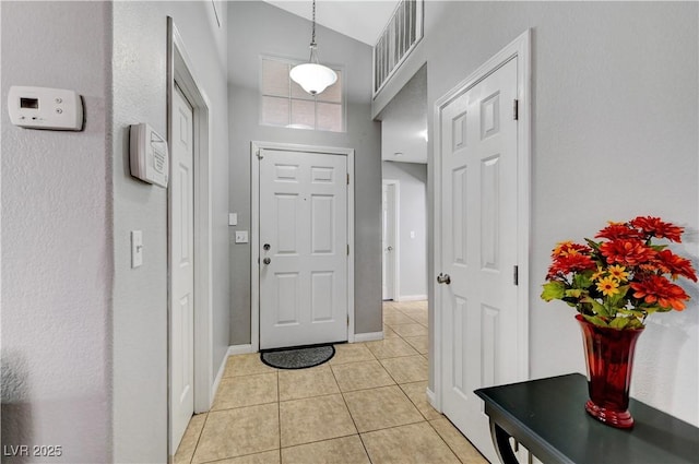 tiled entrance foyer featuring high vaulted ceiling