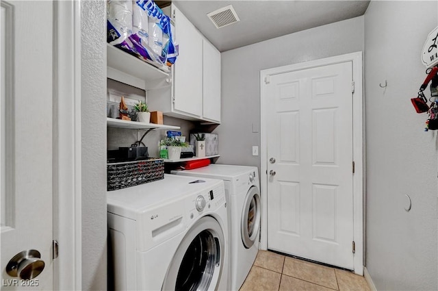 clothes washing area featuring washer and dryer, cabinets, and light tile patterned flooring