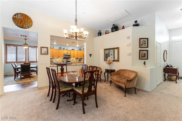 carpeted dining space featuring ceiling fan with notable chandelier