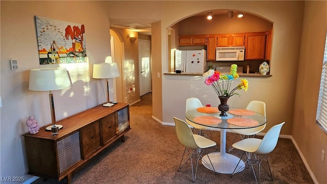 dining room with baseboards, arched walkways, and carpet