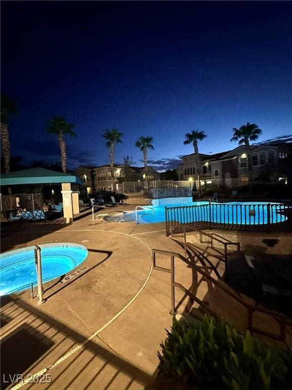 pool at twilight with a community hot tub and a patio area