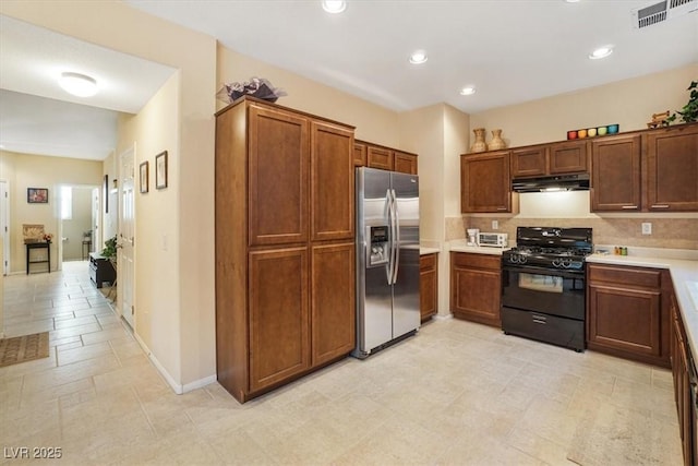 kitchen with gas stove, decorative backsplash, and stainless steel fridge with ice dispenser