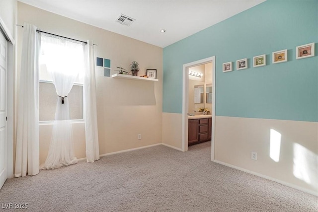 unfurnished bedroom featuring light colored carpet and connected bathroom