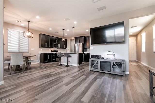 kitchen featuring sink, hanging light fixtures, stainless steel appliances, a kitchen breakfast bar, and a kitchen island