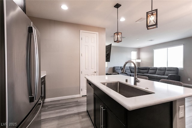 kitchen featuring sink, hardwood / wood-style flooring, hanging light fixtures, stainless steel appliances, and a center island with sink