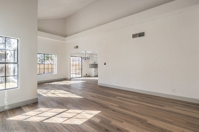 interior space featuring wood-type flooring, a notable chandelier, and a towering ceiling