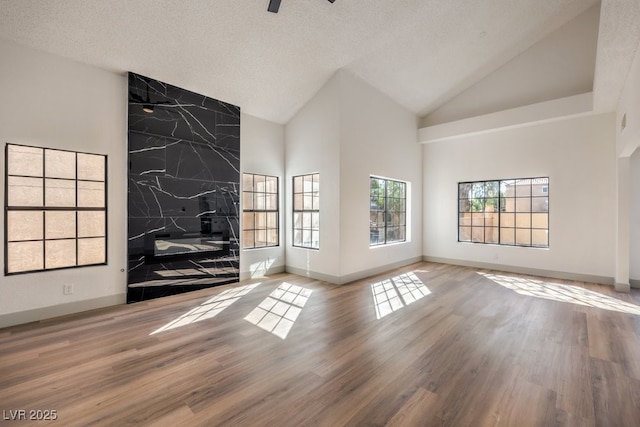 unfurnished living room with a textured ceiling, hardwood / wood-style floors, and high vaulted ceiling