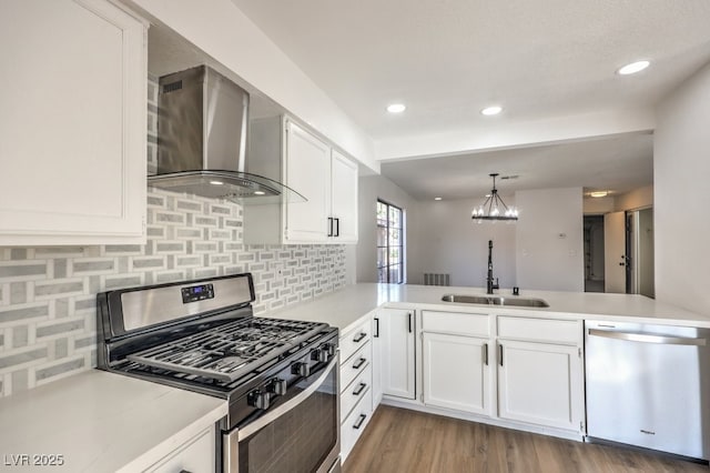 kitchen with appliances with stainless steel finishes, wall chimney exhaust hood, white cabinetry, sink, and kitchen peninsula